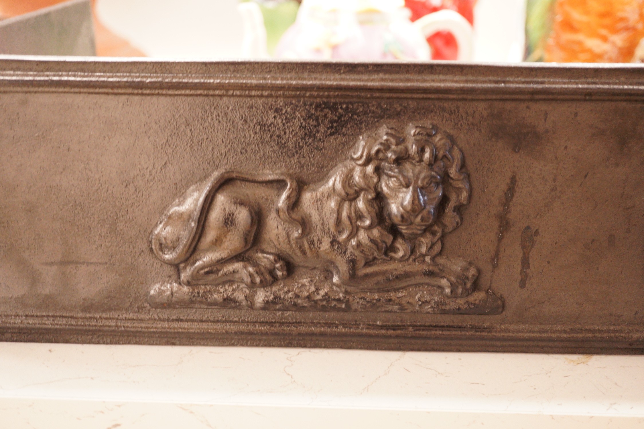 A blackened cast iron fender, of rectangular form decorated with lions, 76.5cm wide, 31cm deep